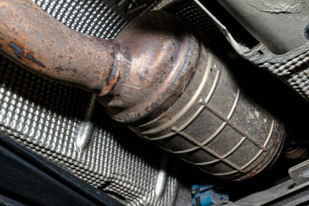 A diesel particulate filter in the exhaust system in a car on a lift in a car workshop, seen from be