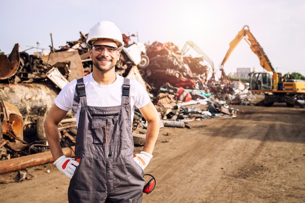 Portrait,Of,Worker,Standing,In,Metal,Junk,Yard,With,Crane